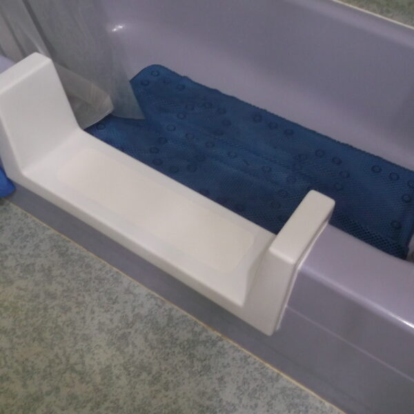 A white bathtub armrest or support attached to the tub edge.